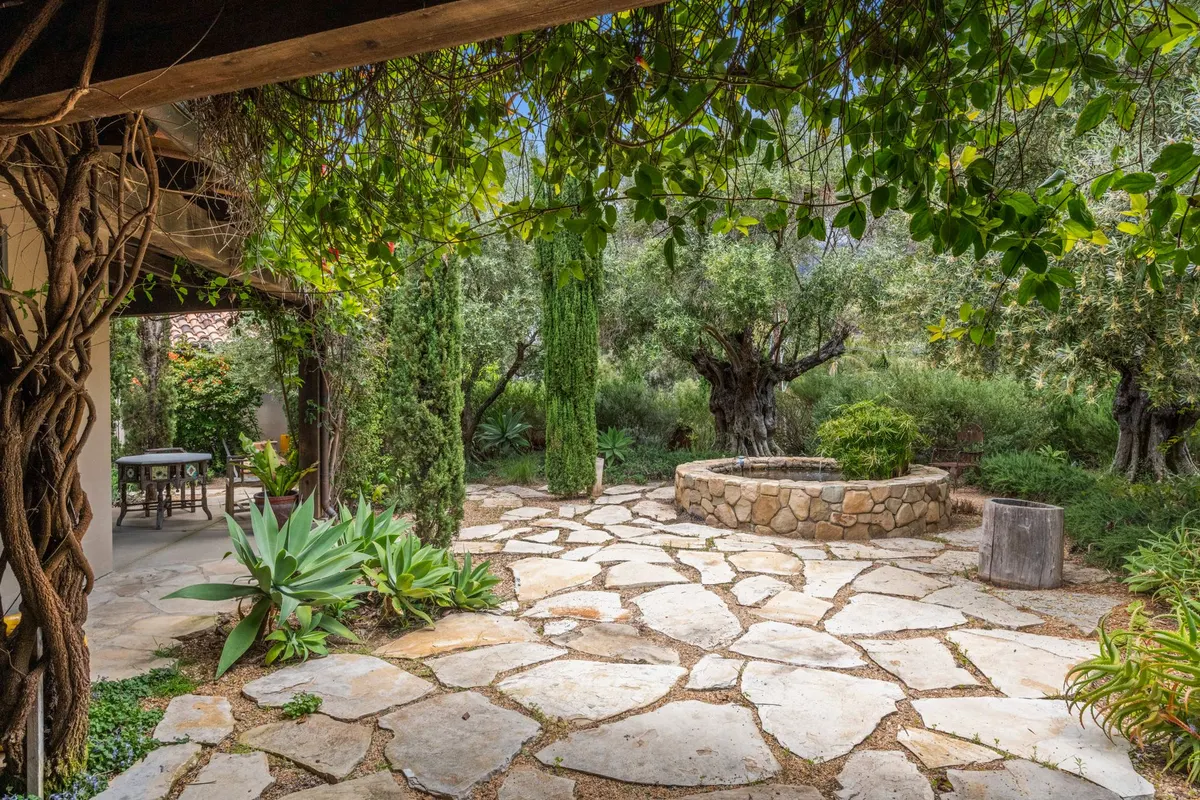 Circular stone patio surrounded by mature plantings