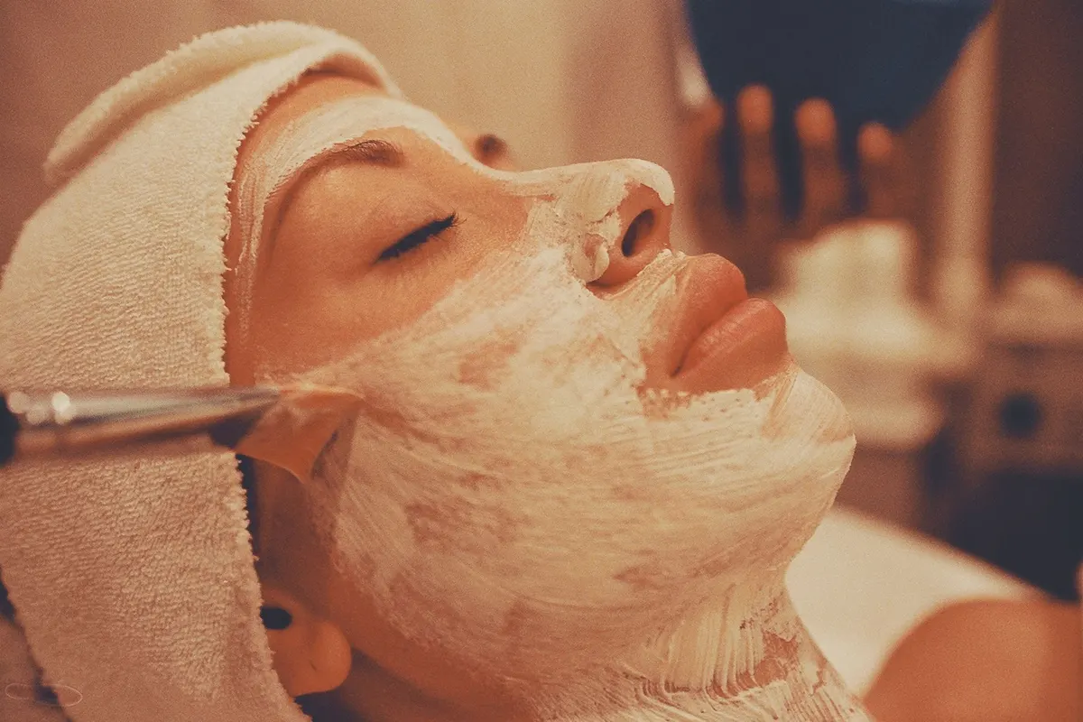 Esthetician applying a cream mask during a facial treatment