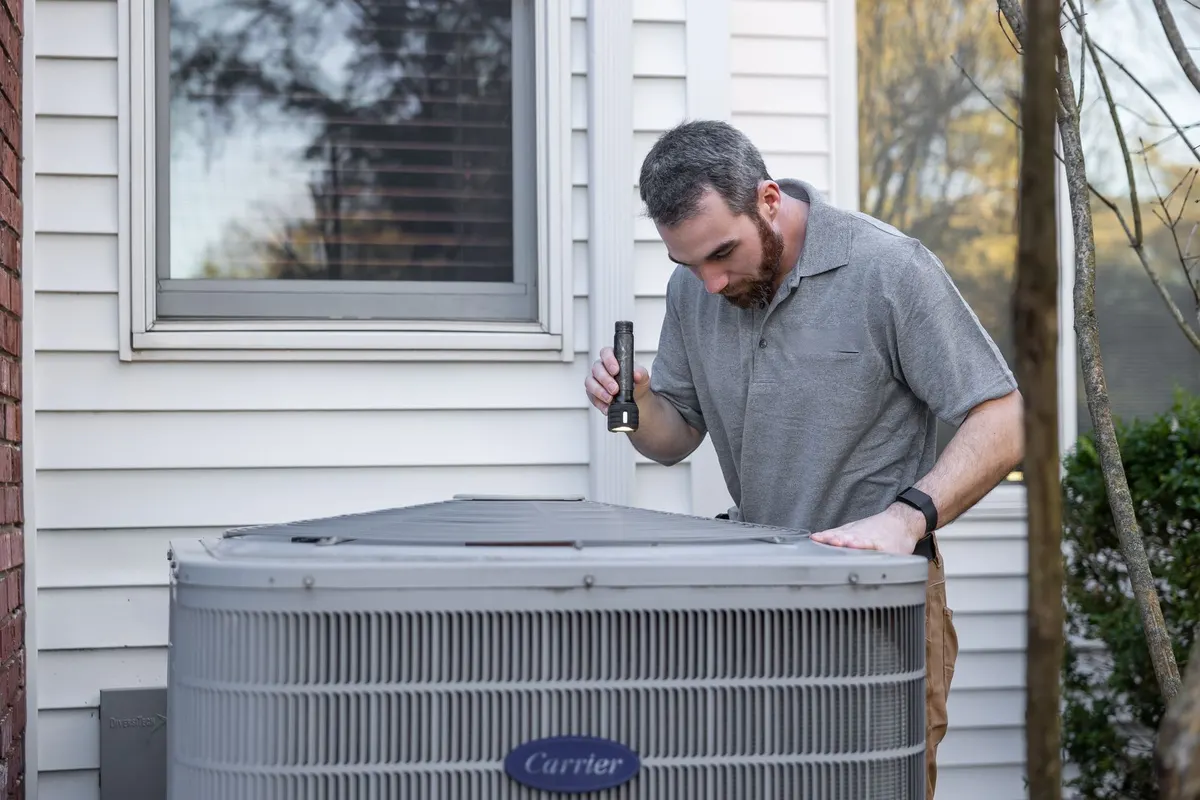 HVAC technician inspecting a residential air conditioning condenser