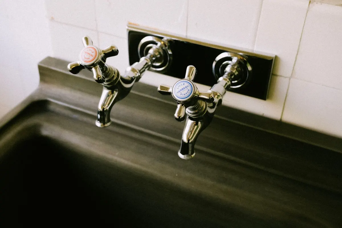 Corroded old two-handle faucet on a stained utility sink