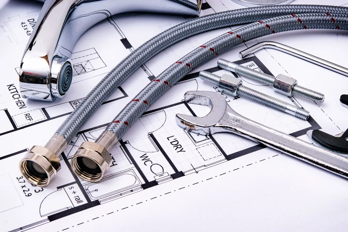 Plumbing fittings and a wrench laid over project blueprints