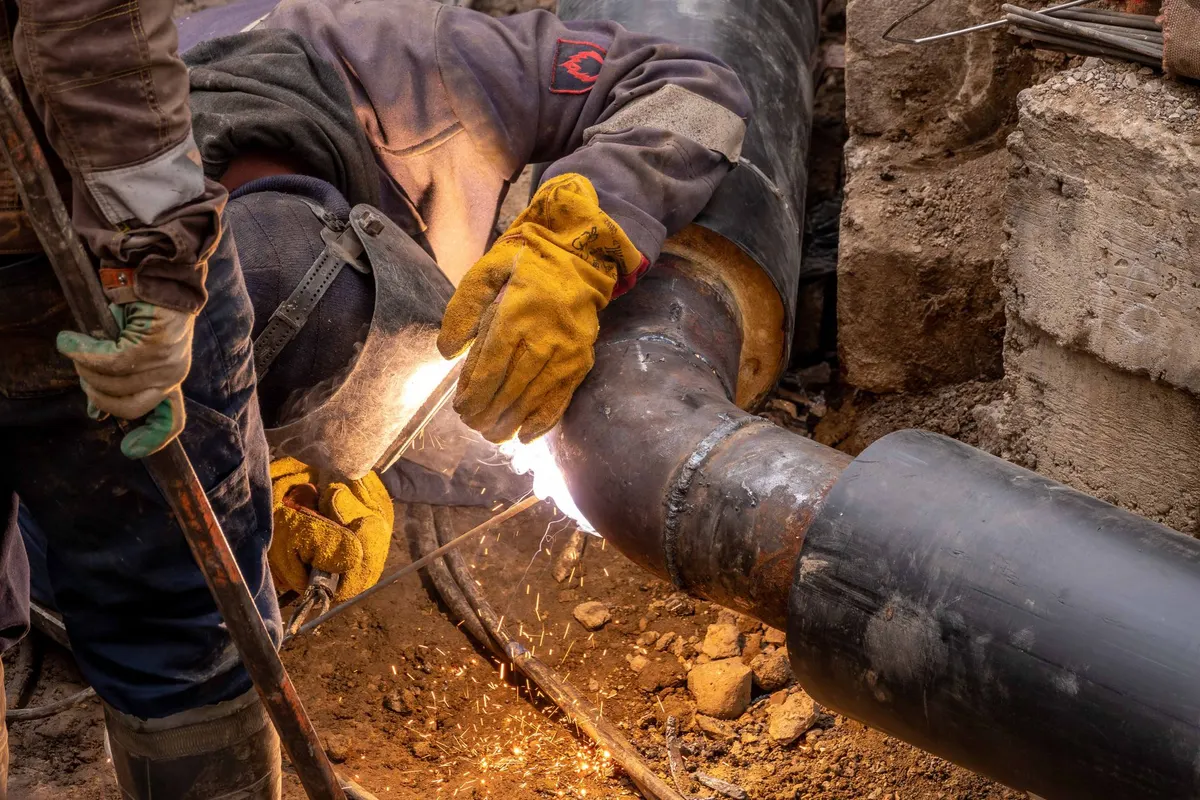 Crew joining a water main line in an excavated trench