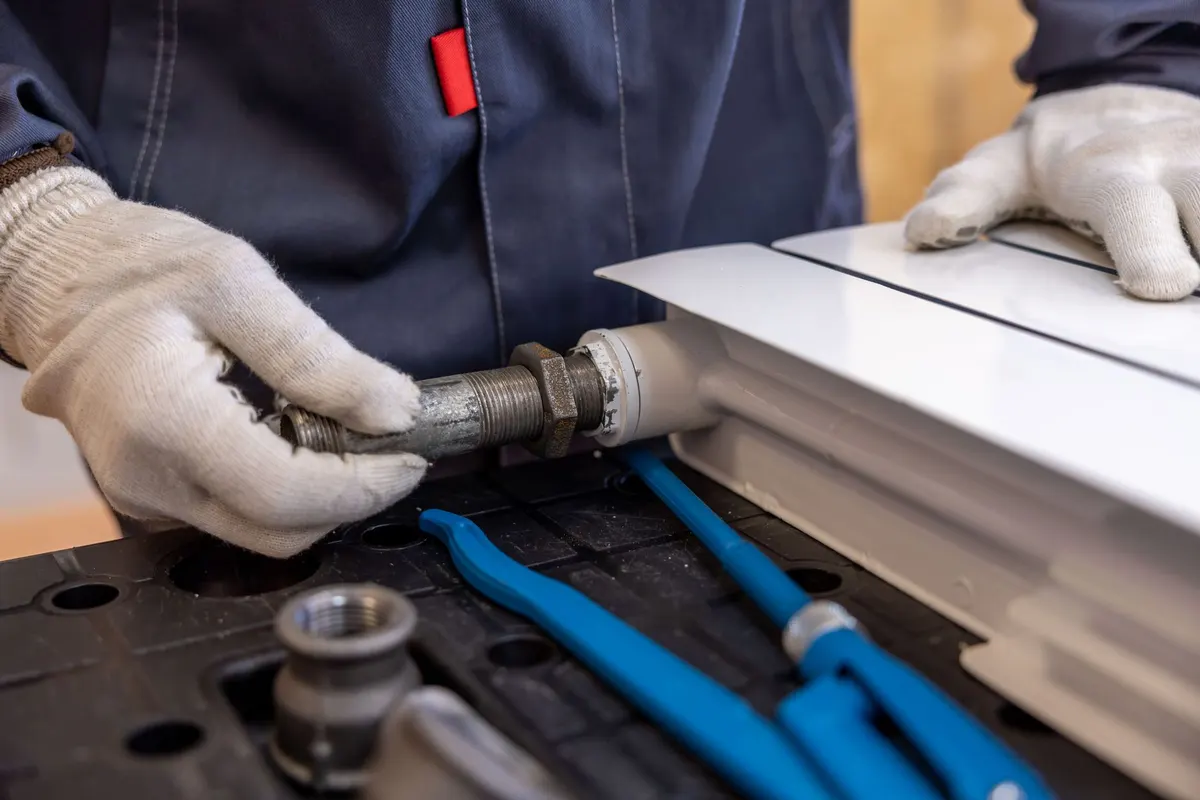 Technician assembling PEX water line fittings on a workbench